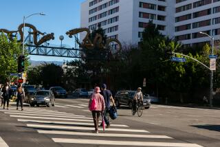 LOS ANGELES, CA - OCTOBER 28: People walk by the Cathay Manor building in Chinatown as owners of the building face allegations that the elevators in the 16-story building for low-income seniors are inoperable and have not been maintained in accordance with the Los Angeles Fire Department fire safety protocols on Thursday, Oct. 28, 2021 in Los Angeles, CA. (Jason Armond / Los Angeles Times)