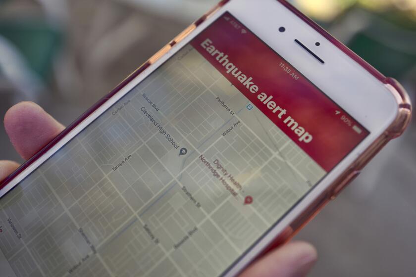 FILE - In this Jan. 3, 2019 file photo a mobile phone customer looks at an earthquake warning application on their phone in Los Angeles. Earthquake early warning alerts will become publicly available throughout California for the first time this week, potentially giving people time to protect themselves from harm, the Governor's Office of Emergency Services said Wednesday, Oct. 16, 2019. Warnings produced by the ShakeAlert system will be pushed through two delivery systems: a cellphone app called MyShake and the same wireless notification system that issues Amber Alerts, meaning people may receive both notifications. (AP Photo/Richard Vogel, File)