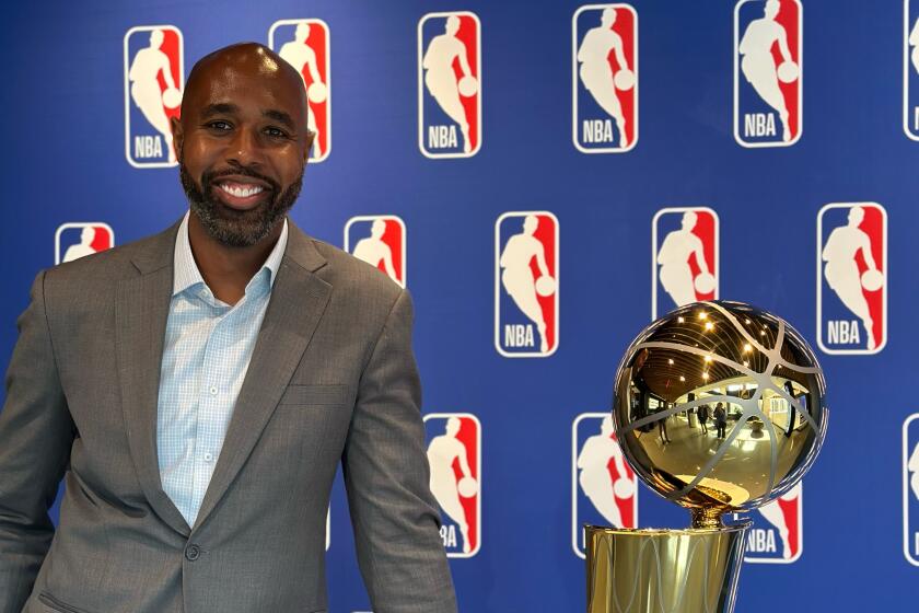 Albert Sanders, NBA executive vice president, stands next to the Larry O'Brien Trophy.