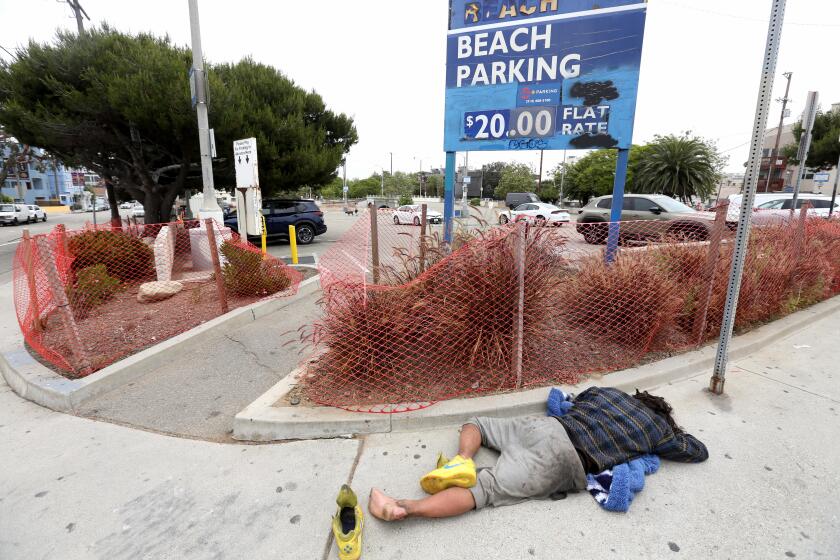 VENICE, CA - JUNE 7, 2024 - A homeless man sleeps on a sidewalk in front of a parking lot where the Venice Dell Project will be built to house the homeless at Venice Blvd. and Main Street in Venice on June 7, 2024. (Genaro Molina/Los Angeles Times)