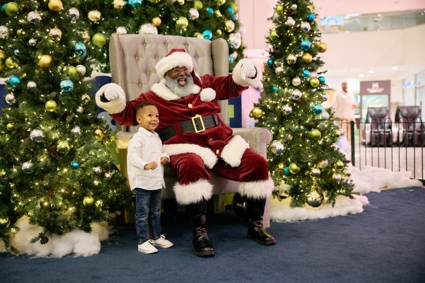 Los Angeles, CA - December 18:Three-year old Shawn poses with Santa Brown. Baldwin Hills Crenshaw Mall on Wednesday, Dec. 18, 2024 in Los Angeles, CA. (Marcus Ubungen / Los Angeles Times)