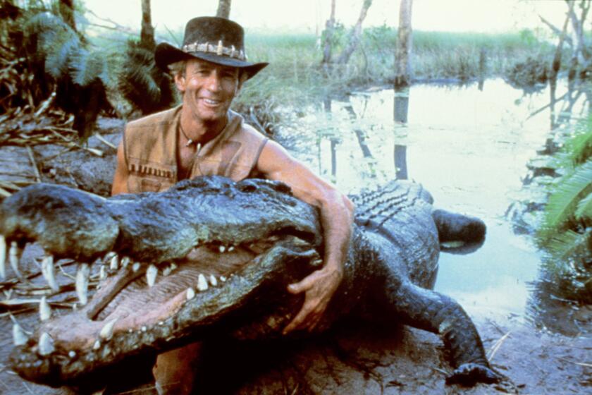 Paul Hogan poses with a model of Burt during filming for Crocodile Dundee in 1985.