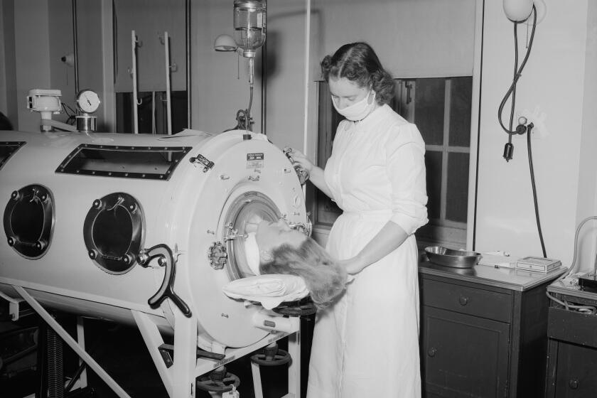 Mrs. George Daniels, 27, of nearby Memphis is shown in an iron lung last night Syracuse, N.Y., November 30, 1954 just before she was transferred to a smaller respirator and enabled to give birth to a 7-pound, 8-ounce daughter. Mrs. Daniels was stricken with bulbar polio last Saturday. Doctors said mother and child were doing well today. The nurse shown is Miss Anita Eastwood. (AP Photo)