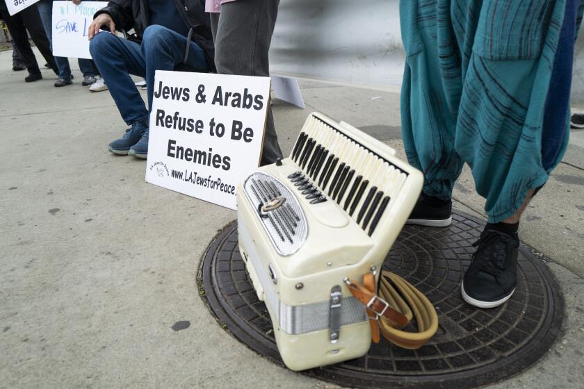 Los Angeles, CA - February 18: An accordion rests at the feet of Keeav Sofer during a Friends of Standing Together L.A. rally for peace in midst of the Israel-Hamas conflict in front of the Federal Building on Sunday, Feb. 18, 2024 in Los Angeles, CA. The group advocates against Israel's war on Gaza, against Hamas, against occupation, for the release of hostages held in Gaza and against the Israeli government. (Carlin Stiehl / Los Angeles Times)